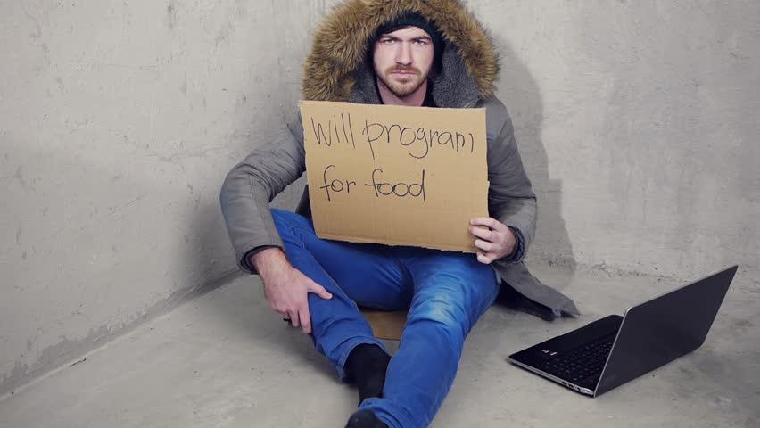 homeless man sitting on the floor with a sign