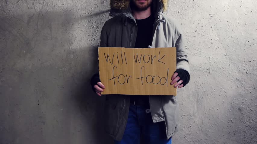 homeless man standing at the wall with a cardboard