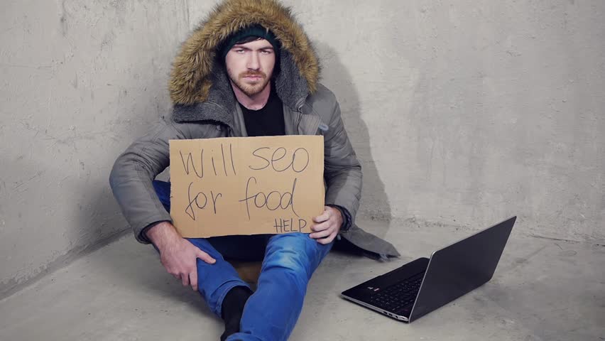 homeless man sitting on the floor with a cardboard asking for a help