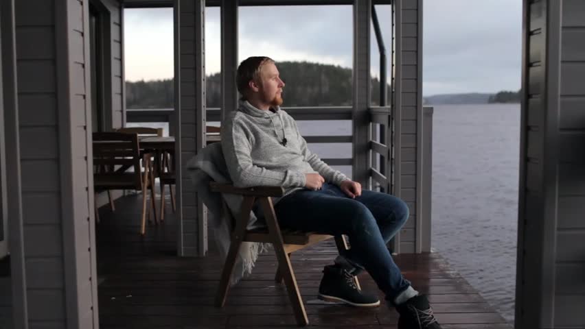 man is resting on the terrace of the house with a view of the lake