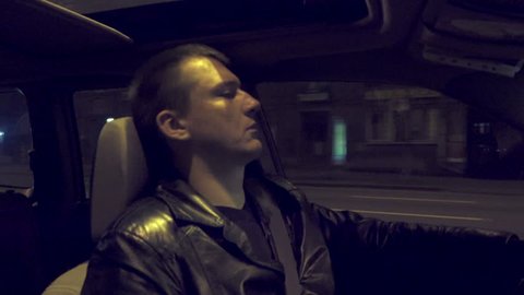 Tired sleepy man drives the car through the night city
