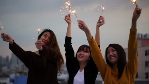 Outdoor shot of young people at rooftop party. Happy group of asia girl friends enjoy and play sparkler at roof top party at evening sunset. Holiday celebration festive party. Teenage lifestyle party., videoclip de stoc
