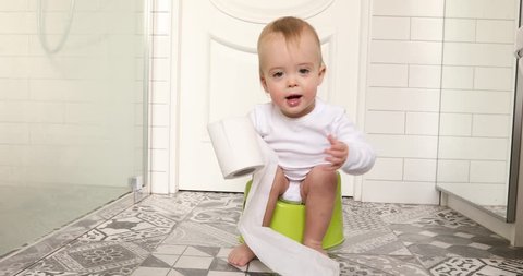 Child sits down and gets up from the chamberpot. Kid plays toilet paper