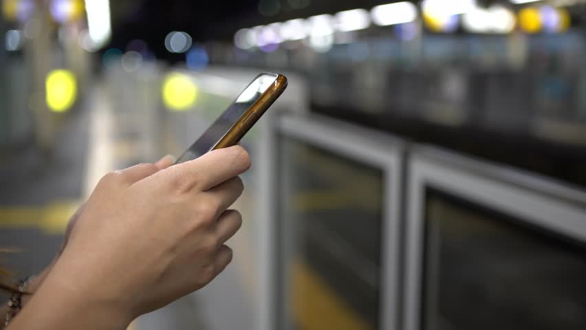 4K Young asian woman using smartphone on active subway platform. As a train passes, girl checks social network and write text done on her phone device, Tokyo train station platform Japan-Dan | Shutterstock HD Video #33122962