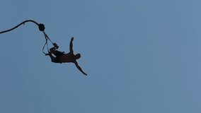 Man is jumping from the top of a Bungee Jumping ; Exhilarating bungee jump from the high platform above sea level, slow motion video clip