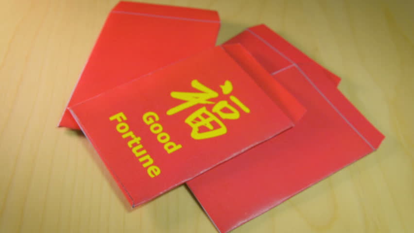 Giving and receiving the red envelope or hong bao during the Chinese New Year. Envelope with the chinese words meaning Good fortune and dollar bills.