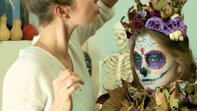 Make-up artist decorating a model with dry flowers after applying Halloween face art - 4K closeup video