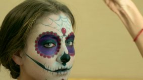 Make-up artist applying custom designed sugar skull mexican day of the dead face make up - close-up video