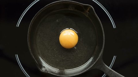 Fried egg on a pig-iron frying pan preparation process time lapse.