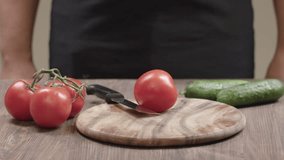 A men's hands cutts tomatoes with chef's knife on cutting board. Video footage in Ultra HD video 4k (3840x2160)