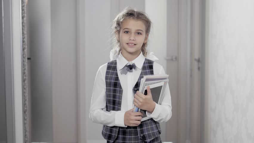 Cute pretty girl with books on white background with books and tablet smiling and happy at home, female little student