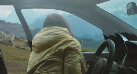 CU  Caucasian female in yellow raincoat getting out of her car on a scenic spot on the mountain top during road trip. 4K UHD RAW 60 FPS SLO MO ஸ்டாக் வீடியோ
