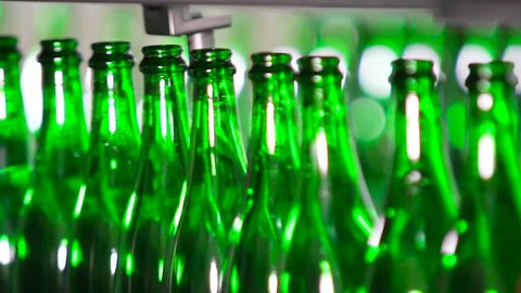 Bottles of green color move along the conveyor at a factory of champagne wines, close-up. Champagne Manufactory.