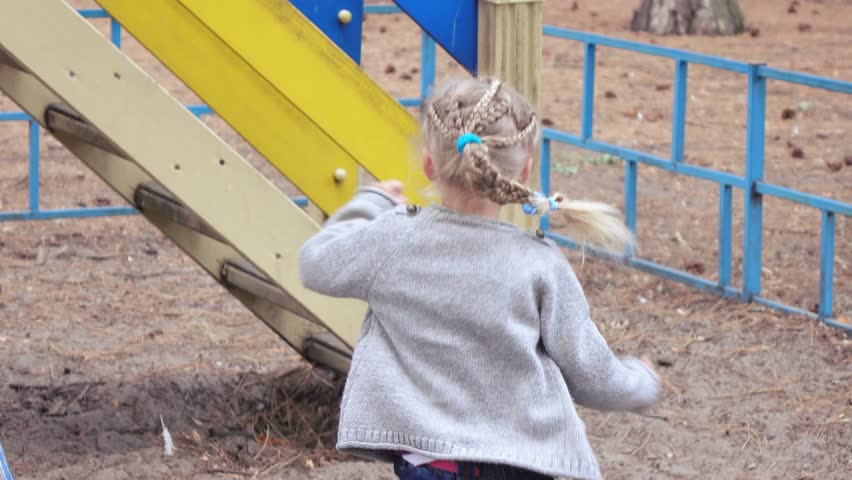 Curly girl playing on the playground in the street