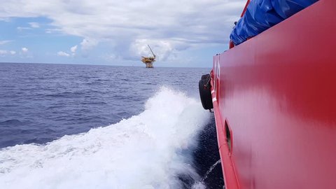 Crew boat sailing to the small offshore platform in the middle of the ocean 
