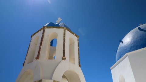 Low angle shot of famous blue dome churches with sun rays in Santorini Island, Greece. Aegean Sea
