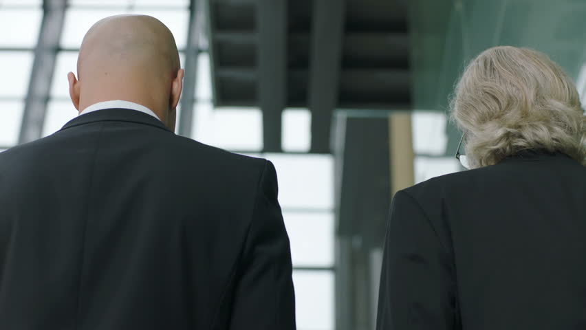 two corporate executives discussing business while descending stairs in modern company. 