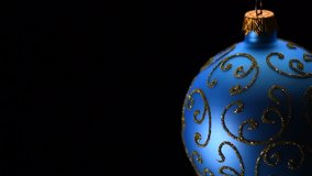 Christmas and New Year Blue color Bauble isolated on black background. Border art design with holiday bauble decoration. Beautiful Christmas tree ball rotated on matte black background. 4K UHD video