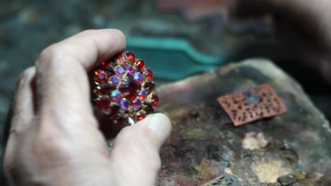 Video shooting of hands of the jeweler from a close distance. The old jeweler is working on the creation of jewelry