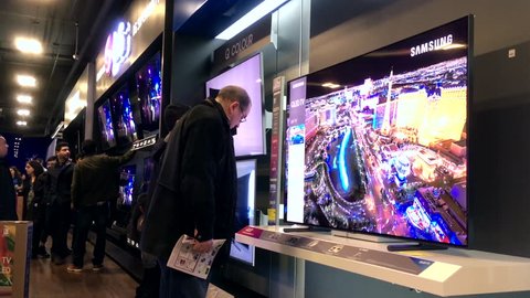 Coquitlam, BC, Canada - November 24, 2017 : Motion of shopper looking new TV to buy inside store on black Friday sale with 4k resolution