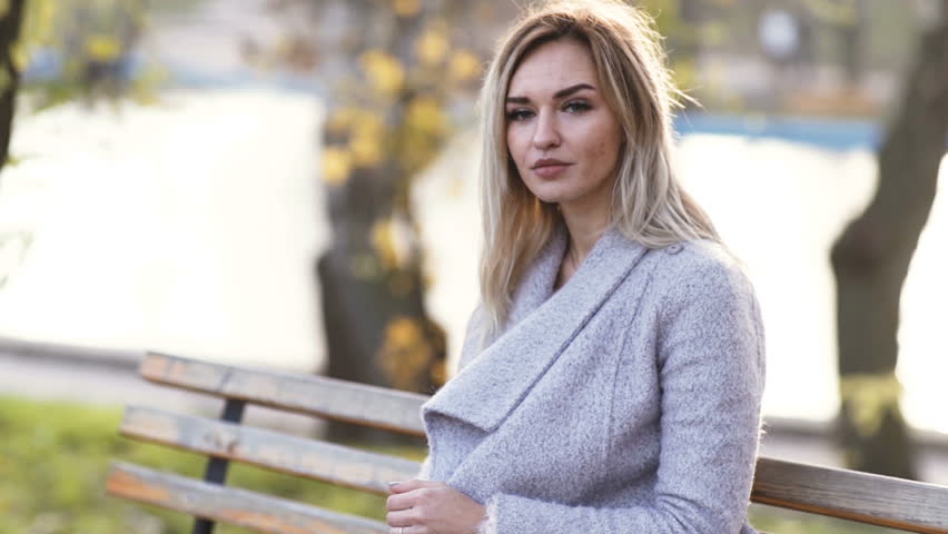 young beautiful business woman drinks alcohol whiskey on nature in the park at sunset after hard work. Autumn background 