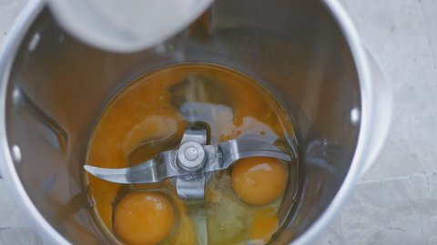Cooking biscuit dough. White sugar pouring in the mixer bowl with broken eggs on the bottom.