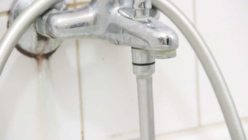 Tap water dripping down the sink, selective focus, white bathroom