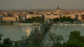 Elevated medium shot of cars passing over Chain Bridge in Budapest. Shot on sunny autumn evening as the sun sets