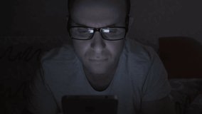 Close up of man with glasses using smartphone. Young man with tablet computer. A man at night on social networks using a smartphone.