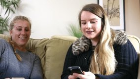 Two young women laughing over funny text message on their phones