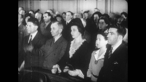 1940s: Men and women in courtroom raise right hands. Statue of Liberty.