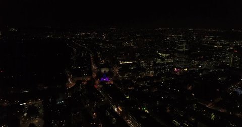 Aerial drone flight above London, uk at night capturing the city lights, landmarks on the Thames and glass office buildings.