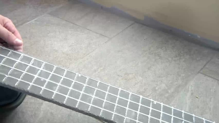 Worker places adhesive to back of ceramic tile strip, and applies it to bottom of wall for decorative edging effect.
