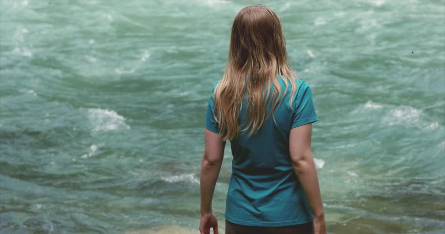 Blonde hair woman walking at river flowing water alone Travel Lifestyle emotions concept 