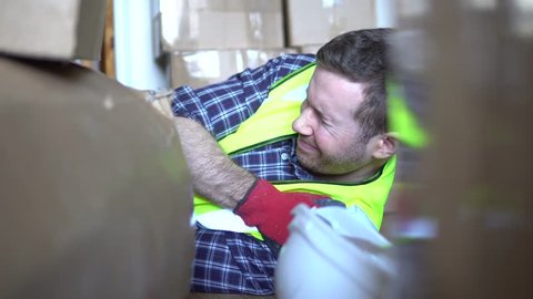 Injury from accident at work. A male warehouse worker man is injured and in pain on floor. For injury compensation claim with lawyer or insurance. A variety of different camera angles available in 4K.