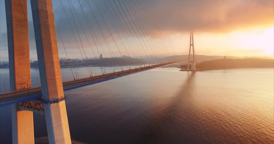 Flying backwards, aerial ascending view of cable-stayed Russian bridge across the Eastern Bosphorus strait on the way to Russian island in Vladivostok, Russia. Morning, sunrise Royalty-Free Stock Footage #33226285