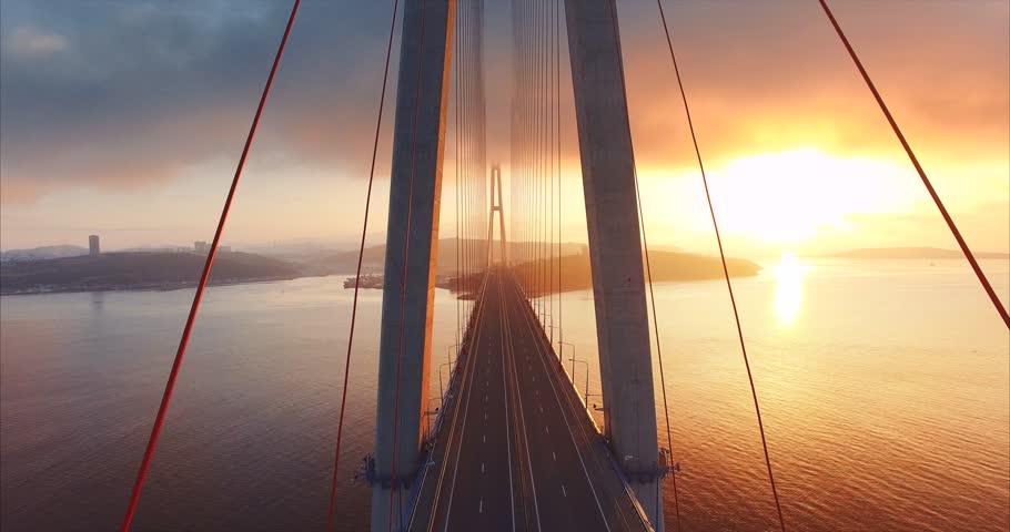 Flying above the road and between cables of cable-stayed Russian bridge across the Eastern Bosphorus strait on the way to Russian island in Vladivostok. Amazing sunrise. Aerial Royalty-Free Stock Footage #33226300
