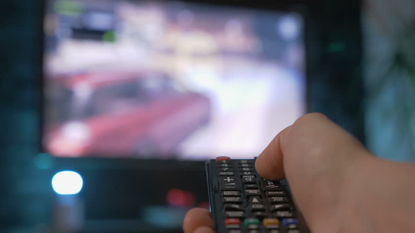 Close up mans hand holding TV remote control and changing TV channels. Blurry background Royalty-Free Stock Footage #33227281