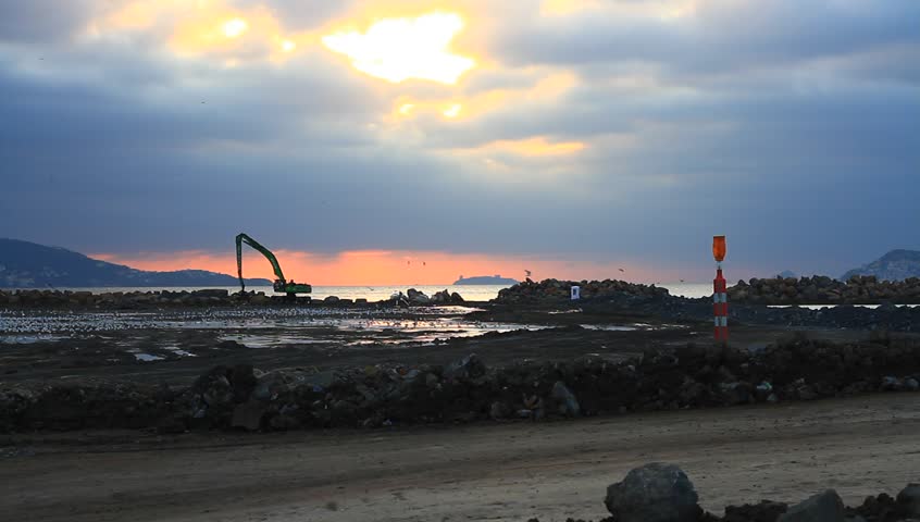 Formation of new lands by filling the sea. Excavator at the construction site by