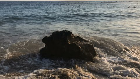 Sea waves covers big stone on the beach