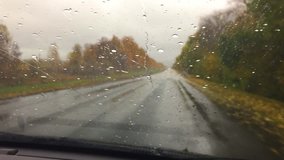 cars go on the road travel asphalt. autumn beautiful view forest, raindrops on the glass car blurred background slow motion video