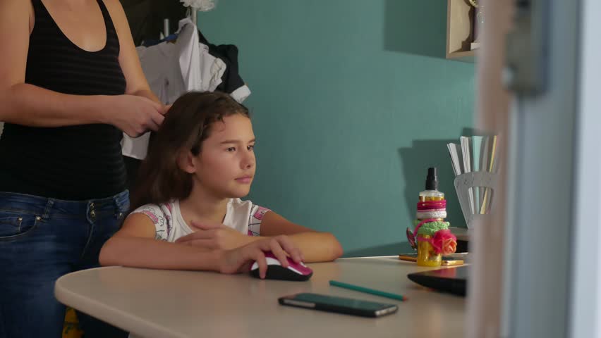 mom woman doing her hairstyle to her little girl teenager indoor