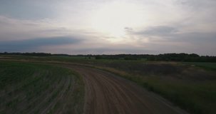 Flying over dirt roads, green fields and farm land