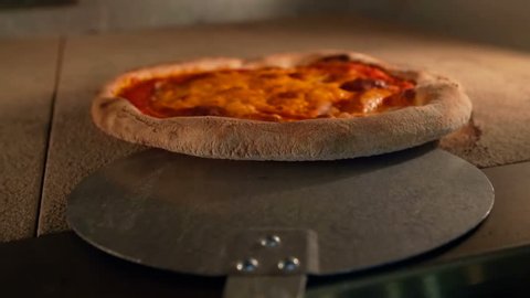 Taking out a pizza from the oven. food, italian kitchen and cooking concept - peel placing pizza baking out of  oven at pizzeria - point of view shot - POV