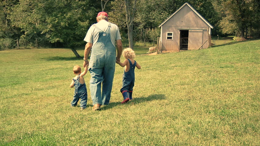 Grandchildren spending time with granddad on the farm. Old farmer taking time with grandchildren on hobby farm. Young and old having quality time together. 