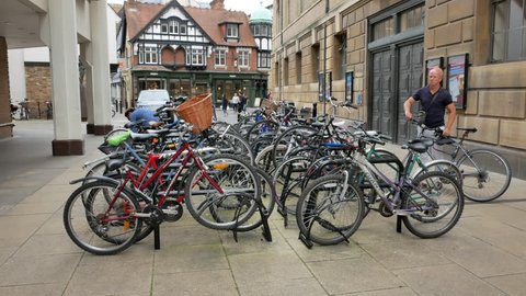 CAMBRIDGE, EAST OF ENGLAND / UNITED KINGDOM - AUGUST 20, 2017: Man gets the bicycle from the row of bicycles at the center of Cambridge, UK on August 20, 2017.