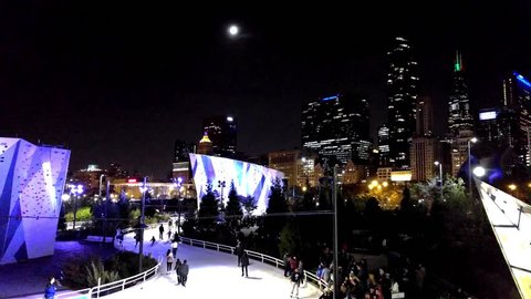 CHICAGO, IL-November 24, 2017. Ice skating at Maggie Daley Park's Skate Ribbon. The urban skyline and moon in the background.