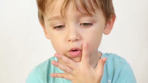 A close-up of a child with an insult, puffed up lips. The child is thoughtful, does not want to hear anybody, keeps fingers at the mouth