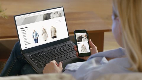 Woman Holds Smartphone and Has Laptop on Her Knees, Browses Online Store that Sales Fashionable Clothes. 