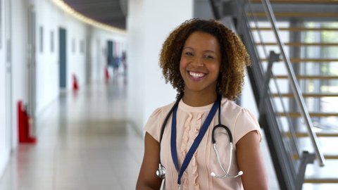 Portrait Of Female Doctor Walking Towards Camera And Smiling